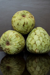 custard apple, tropical fruits on dar background with reflections