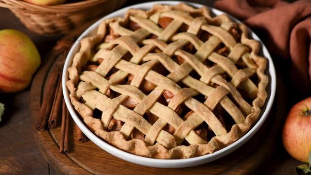 Traditional apple pie pastry on wooden table. Rotating table with food. Autumn comfort food