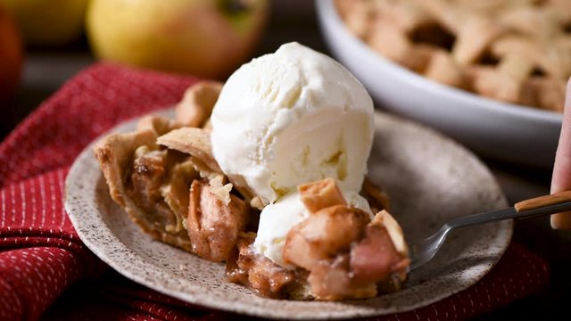 Traditional american apple pie with ice cream. Take a bite of pie with fork. Eating apple pie