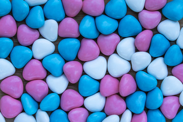 Fototapeta na wymiar Background in the form of hearts of milk chocolate, covered with multi-colored glaze of lilac, blue and white colors, top view