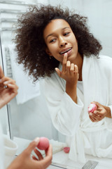 Lips skin care. Woman applying lip balm in bathroom portrait