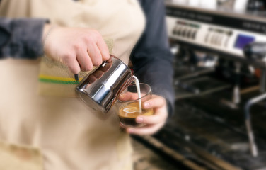 Barista makes latte coffee with milk in cafe closeup