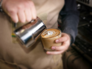 Barista makes latte coffee with milk in cafe closeup
