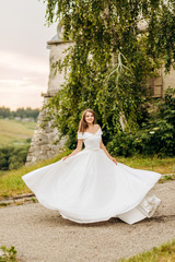 Amazing bride in a lush dress whirls near the castle