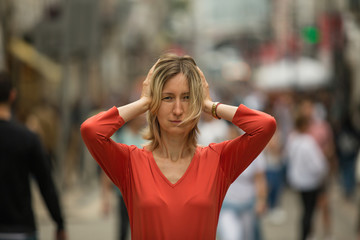 Panic attack in the street. Woman covers his ears with hands at standing in the middle of a busy street. - obrazy, fototapety, plakaty