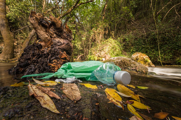 Abandoned garbage on the shore of a stream of clean water.