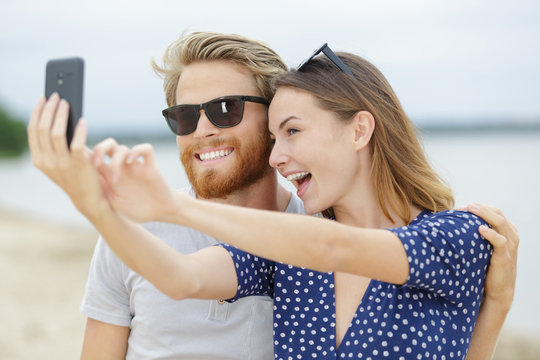 two lovers making a selfie photo on a beach