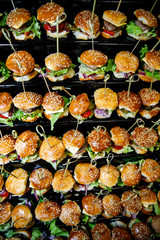 mini burgers with grilled mackerel, tartar sauce, fresh cucumber and ice salad. Close up of mini hamburgers at catering event on some festive event, party or wedding reception