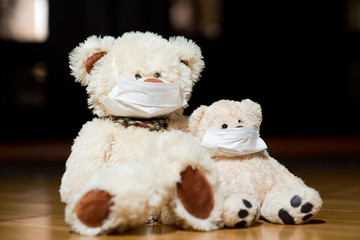 Two teddy bears in medical masks are sitting near the door, close up