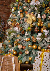 A beautiful Christmas tree stands at home, it is decorated with New Year's toys, snow and an angel, under the tree there are many gifts in a beautiful package that are tied with holiday ribbons. The c