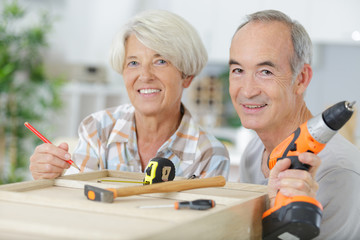happy older couple holding diy tools
