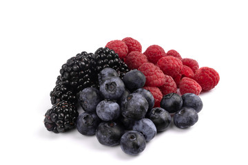 on a white background, ripe and healthy berries of red raspberry, dark violet blackberry and blueberry are gathered together