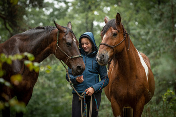 Mädchen mit Pferden im regnerischen Wald - obrazy, fototapety, plakaty