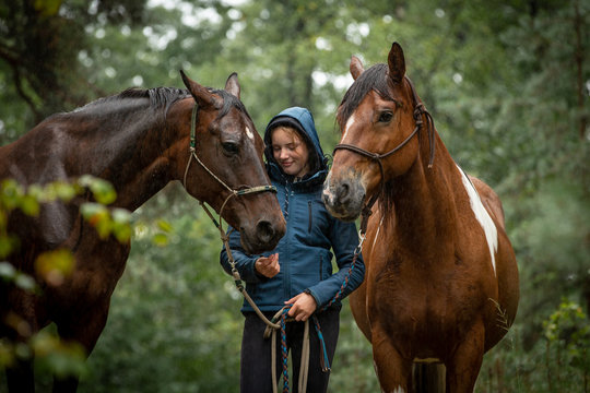 Mädchen mit Pferden im regnerischen Wald