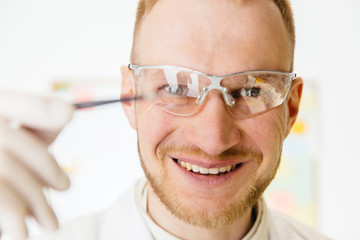 Man wearing white robe holding tweezers.