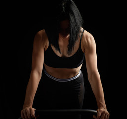 Obraz premium young beautiful athletic girl with muscles in a black bra is wrung out in her arms