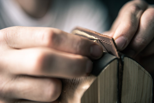 a tanner in a workshop makes a wallet from genuine leather in a special clip