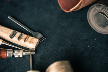 background of black genuine leather with leather tools with brown tinting