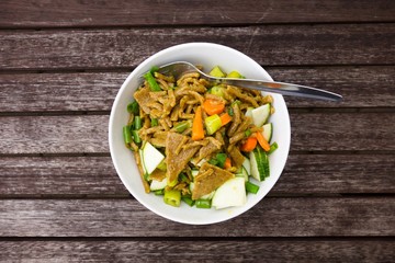 Homemade healthy pasta with vegetable. Indian style. Turmeric, zucchini, carrot, pepper. Served on a wooden table, top view.