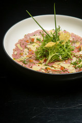 Tuna carpaccio with Italian herb dressing served on the wooden table. Exquisite dish. Creative restaurant meal concept.	