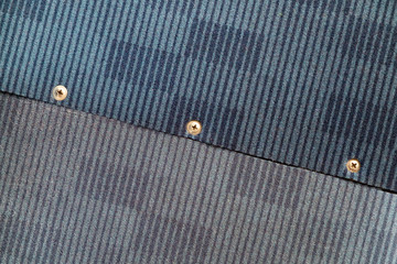 two pieces of dark blue fabric are connected by means of metal screws. The fabric is slightly different in color from each other