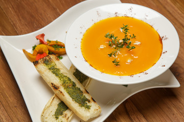 Roasted pumpkin cream soup served with bread on the restaurant table. Exquisite dish. Creative restaurant meal. Fine dining concept.	