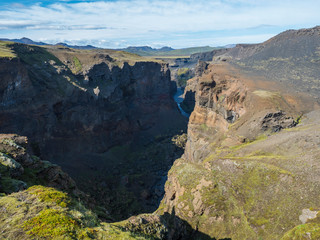 View on majestic Markarfljotsgljufur Canyon gorge and river with green moss covered hills near Botnar camp at Fjallabak Nature Reserve in Highlands of Iceland, blue sky background