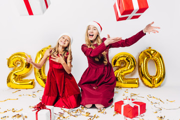 a happy mother and little daughter in Santa hats, having fun sitting on a white background with...