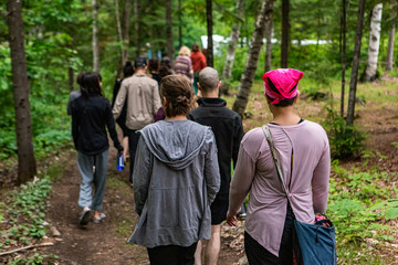 Diverse people enjoy spiritual gathering A large group of multigenerational people are seen from behind, walking together along a woodland trail during a multicultural and native retreat in nature.