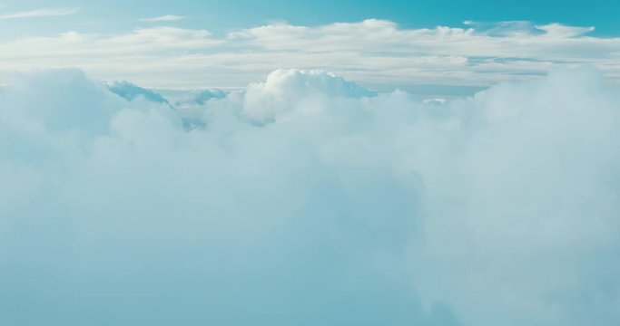 Aerial view ascending over misty blue clouds to reveal more clouds