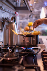 girl cooks spaghetti in a stainless steel pan