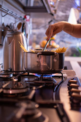 girl cooks spaghetti in a stainless steel pan
