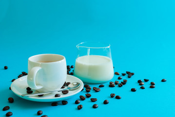 coffee beans around a cup of coffee with a laboratory glass full of milk