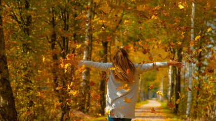 CLOSE UP: Woman with her arms outstretched lets the dry leaves fall on her.