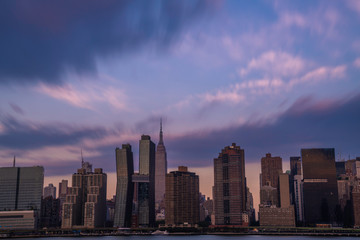 Midtown Manhattan skyline viewed from Long Island City, featuring dramatic sky over the city at sunrise