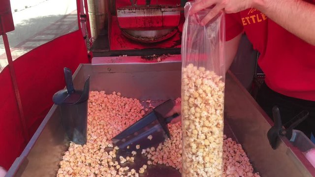 Circus worker fills up plastic bag of popcorn for resale to customers at event.
