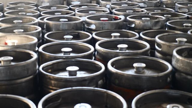 Beer kegs in sunlight stand together in brewery. Steel barrels in wholesale warehouse ready for delivery. Beer factory. Shot in 4k