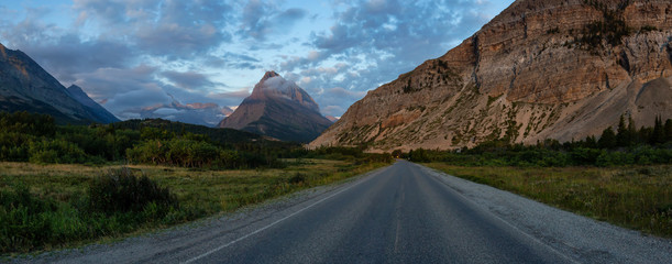 Beautiful Panoramic View of a Scenic Road in the American Rocky Mountain Landscape during a Cloudy Morning Sunrise. Taken in Glacier National Park, Montana, United States.