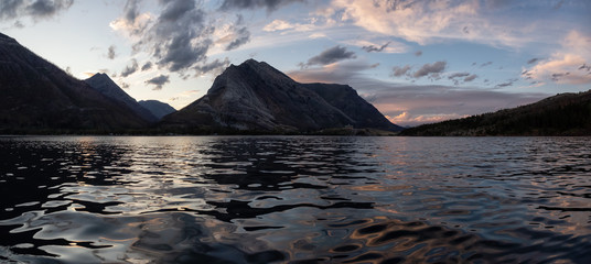 Panoramic View of Glacier Lake surrounded by the beautiful Canadian Rocky Mountains during a cloudy...