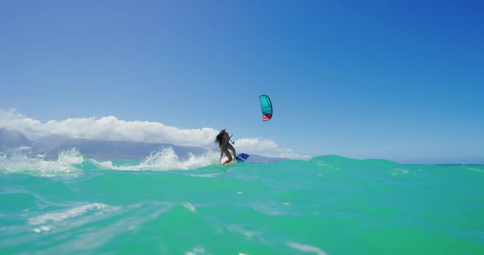 Young active woman riding by smiling kitesurfing in the ocean on a sunny day, fun times doing extreme sports