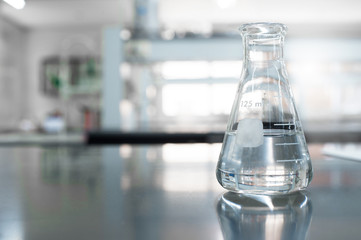 single glass flask with water in chemistry education laboratory background