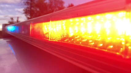 Law enforcement police lights flashing up close in red and blue on top of cruiser in late afternoon lighting. 