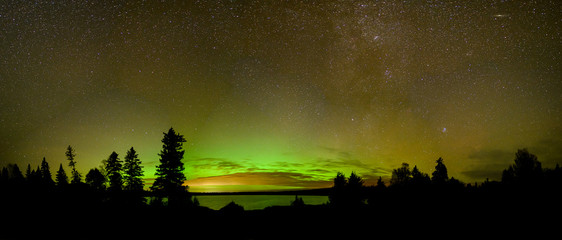 Bright green and orange Aurora (Northern Lights) , stars and clouds reflecting in a calm lake.  Includes Andromeda galaxy.  