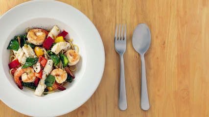 food background of spices green pepper spaghetti with variety of seafood shirmp, fish and squids on wooden table