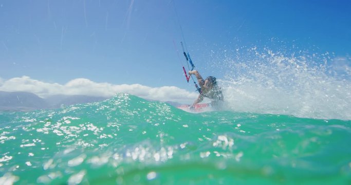 Young woman kitesurfing and smiling, riding by the camera and splashing, extreme sports on a sunny day