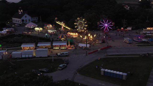 Flyover of small community fair with rides at night