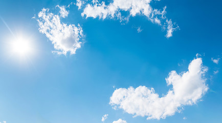 sun and white clouds dancing in a  circle in a blue sky 