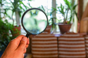 Indoor damp & air quality (IAQ) testing. Searching for signs of moisture inside a family home, using a magnifying glass in a point of view (POV) perspective, with blurry background and copy-space.