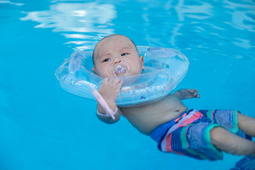 Cute little baby with inflatable neck ring in swimming pool