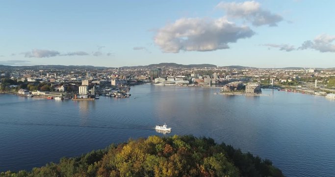 Cinema 4K drone shot with forward tilt reveal motion of Hoved&oslash;ya island, a ferry, the Oslofjord and the Bj&oslash;rvika project with the Lambda Munch Museum and Opera House in autumn fall, in Oslo Norway.